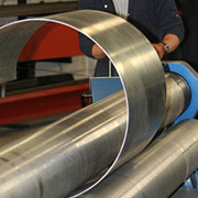 A man rolling a piece of steel into a tube.